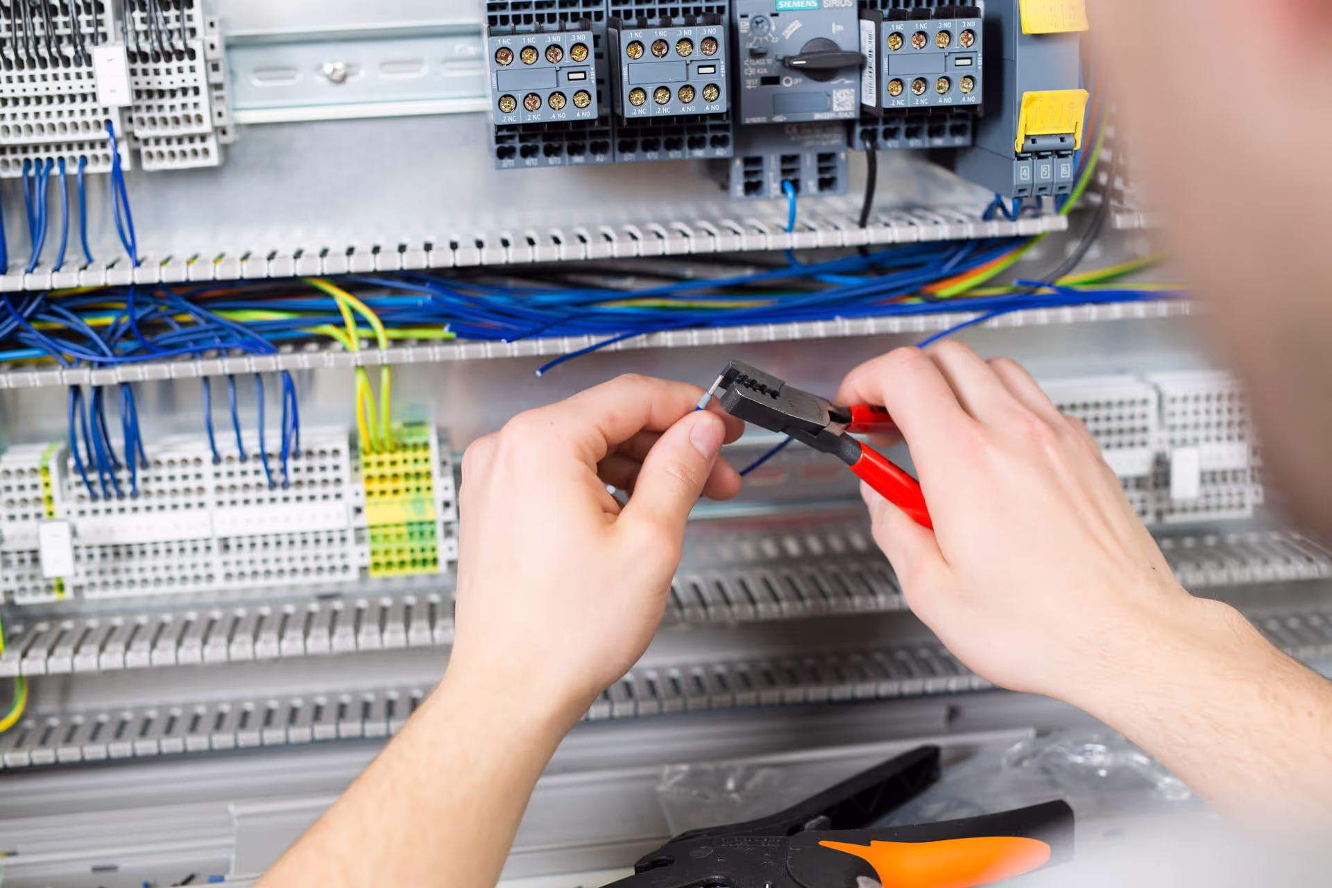 Elektroniker mit Verkabelung an Schaltschrank.